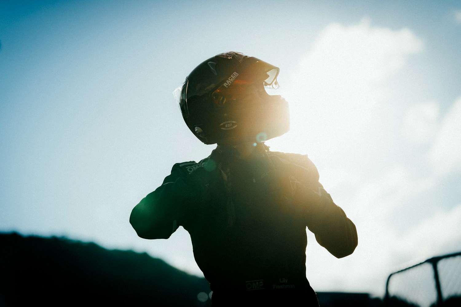 Lily silhouetted against the sun, fastening her helmet — by Dane Scott
